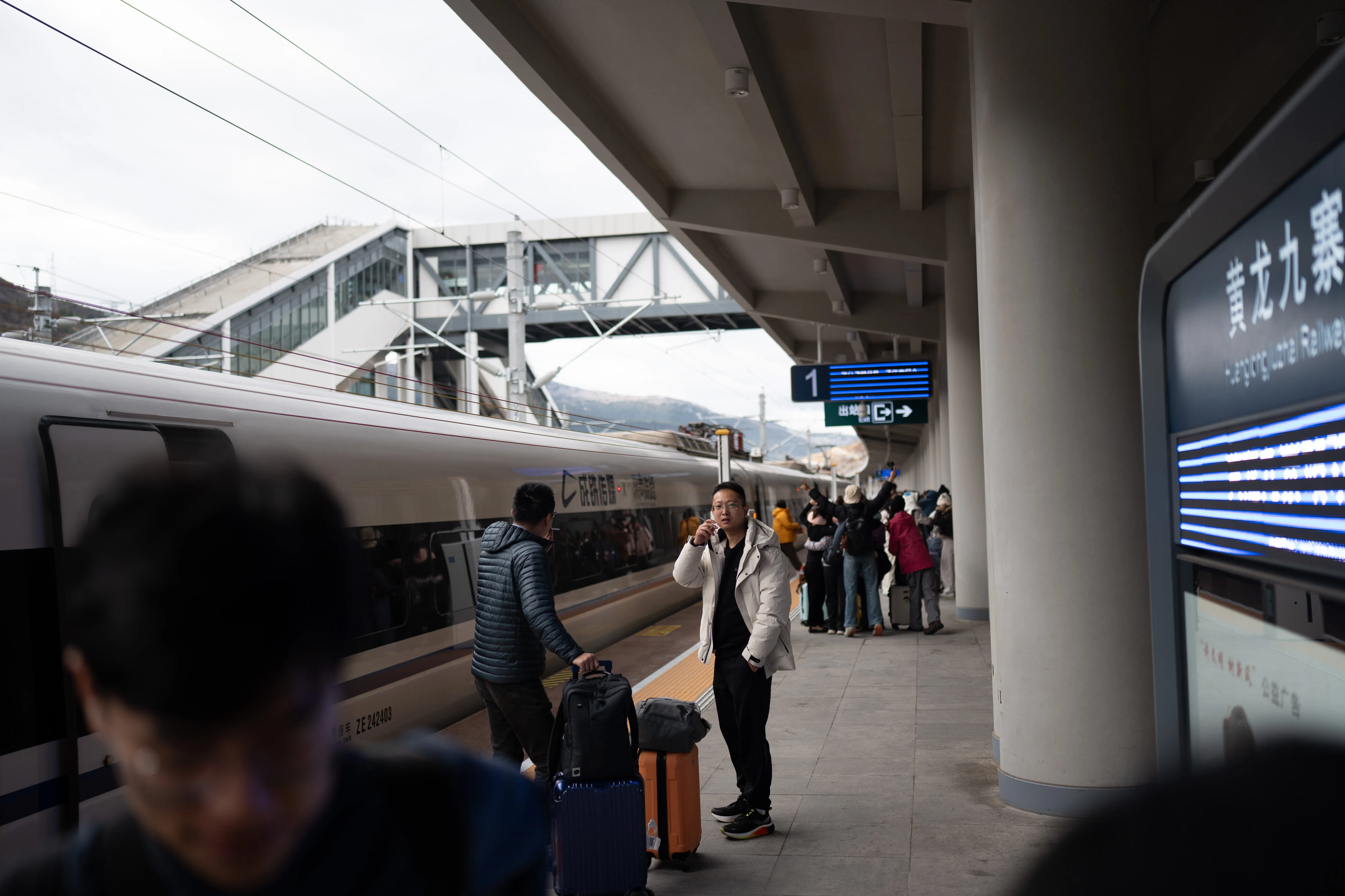 High-speed train pulling into the platform, passengers waiting