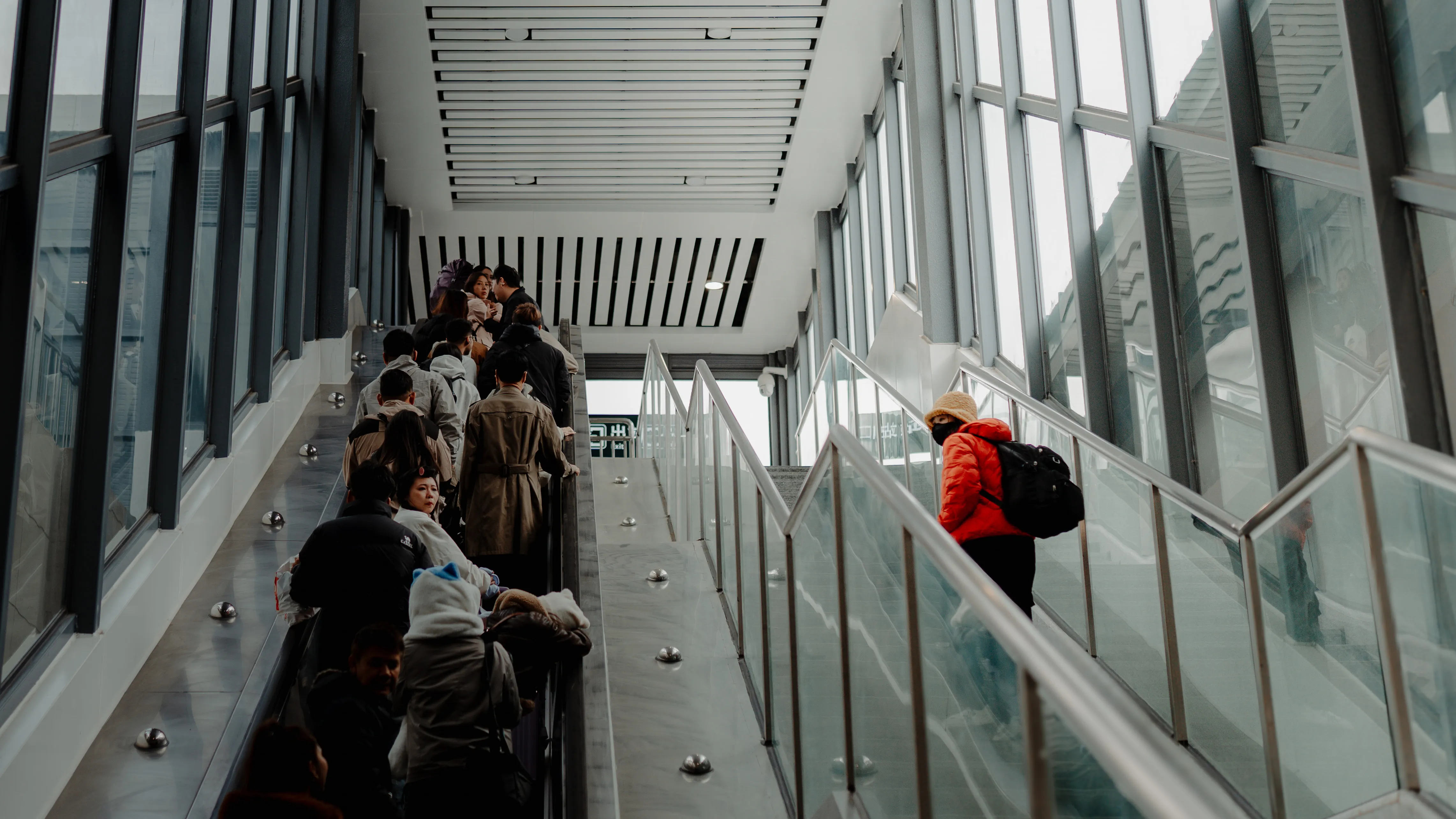 Travellers descending the long walkway out of the station