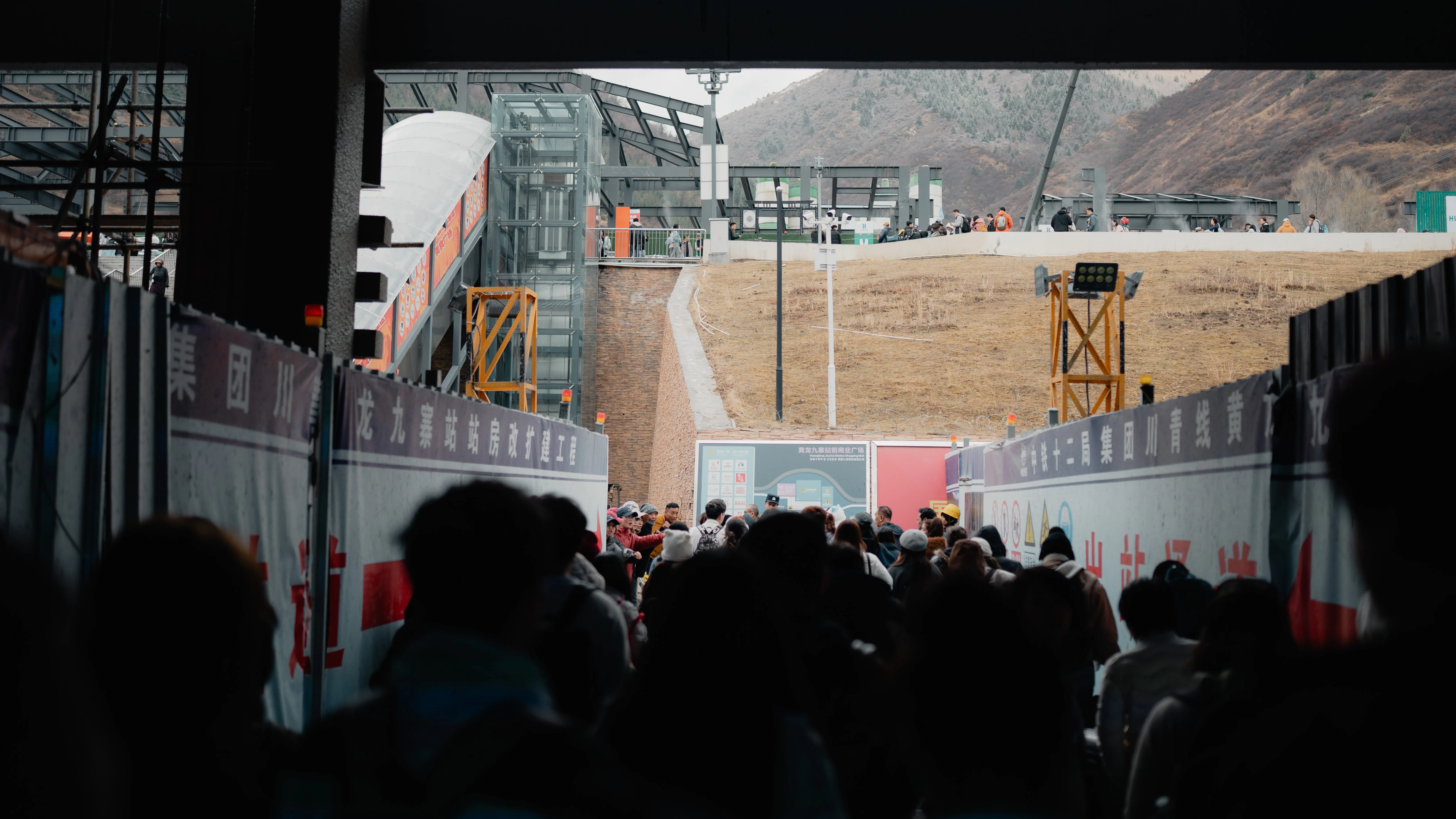 Crowd streaming out of a tunnel toward the mountains