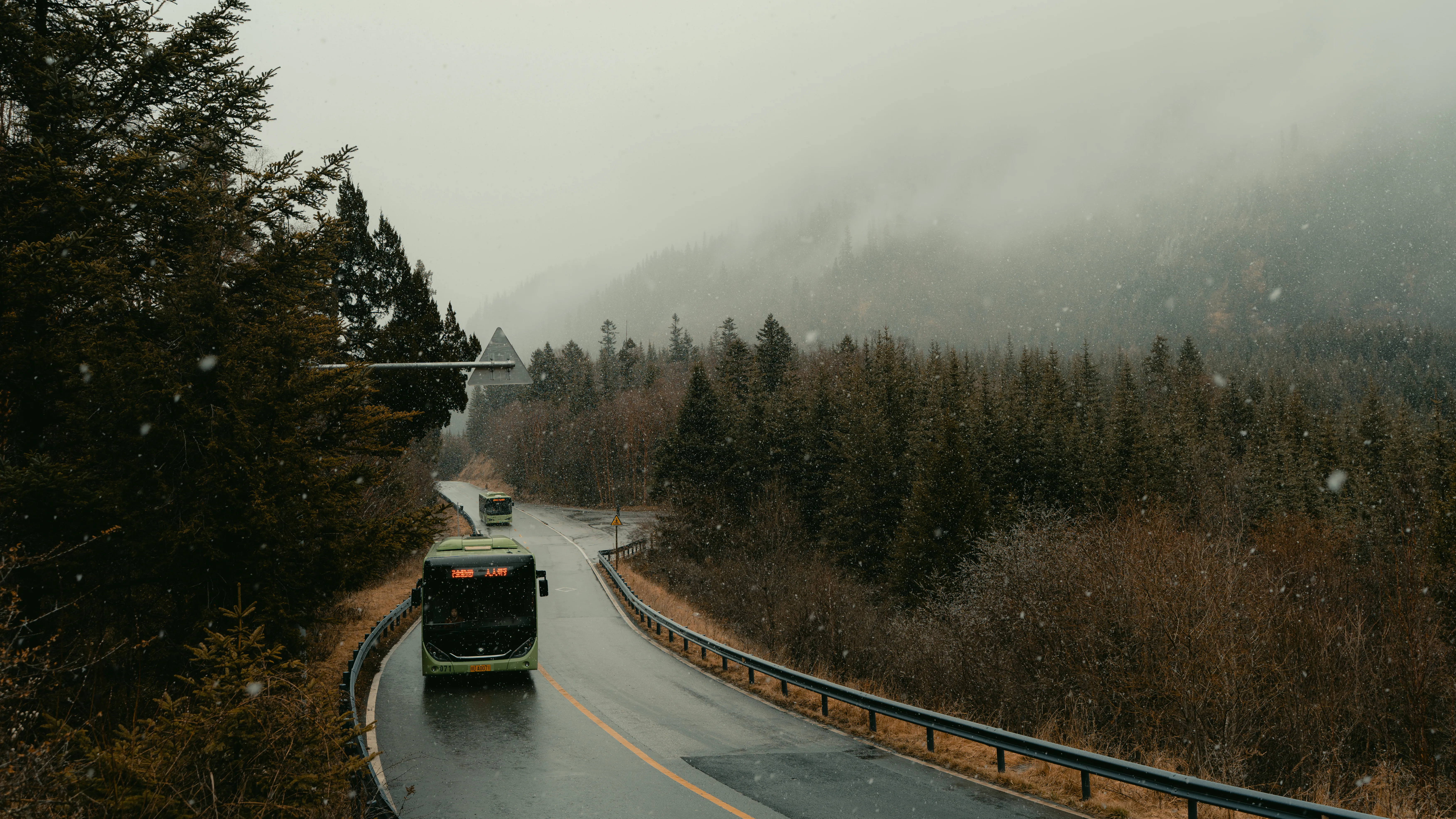 A coach on a mountain road in the first flurries of snow